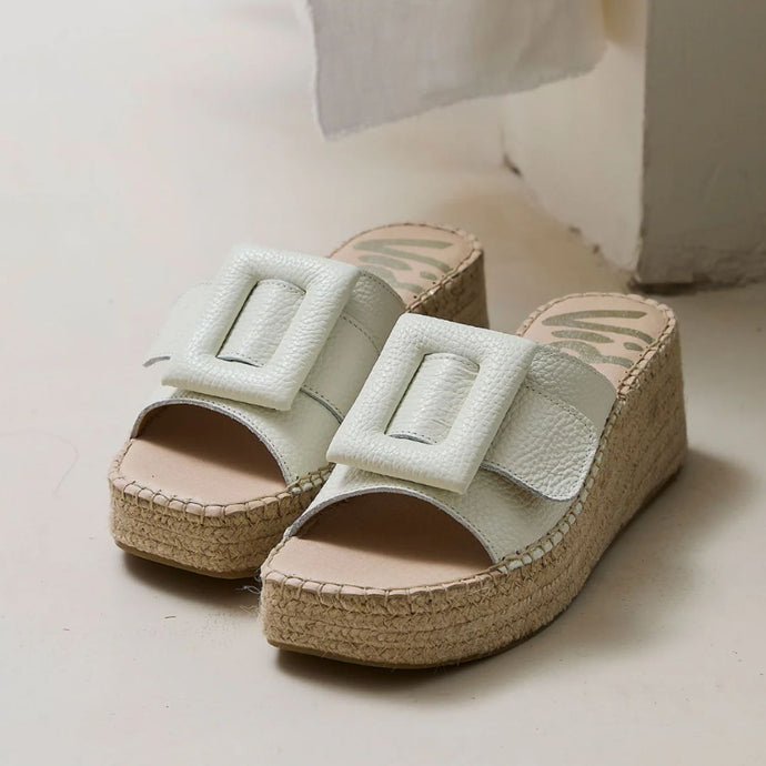 Espadrille wedge slip on sandals with white leather square buckles on a neutral background